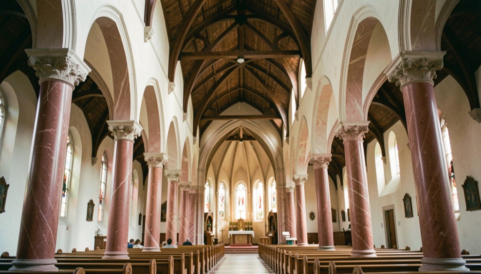 Immagine illustrativa: interno di chiesa a tre navate, colonne monolitiche in marmo rosso e archi a sesto acuto, copertura lignea a capriate